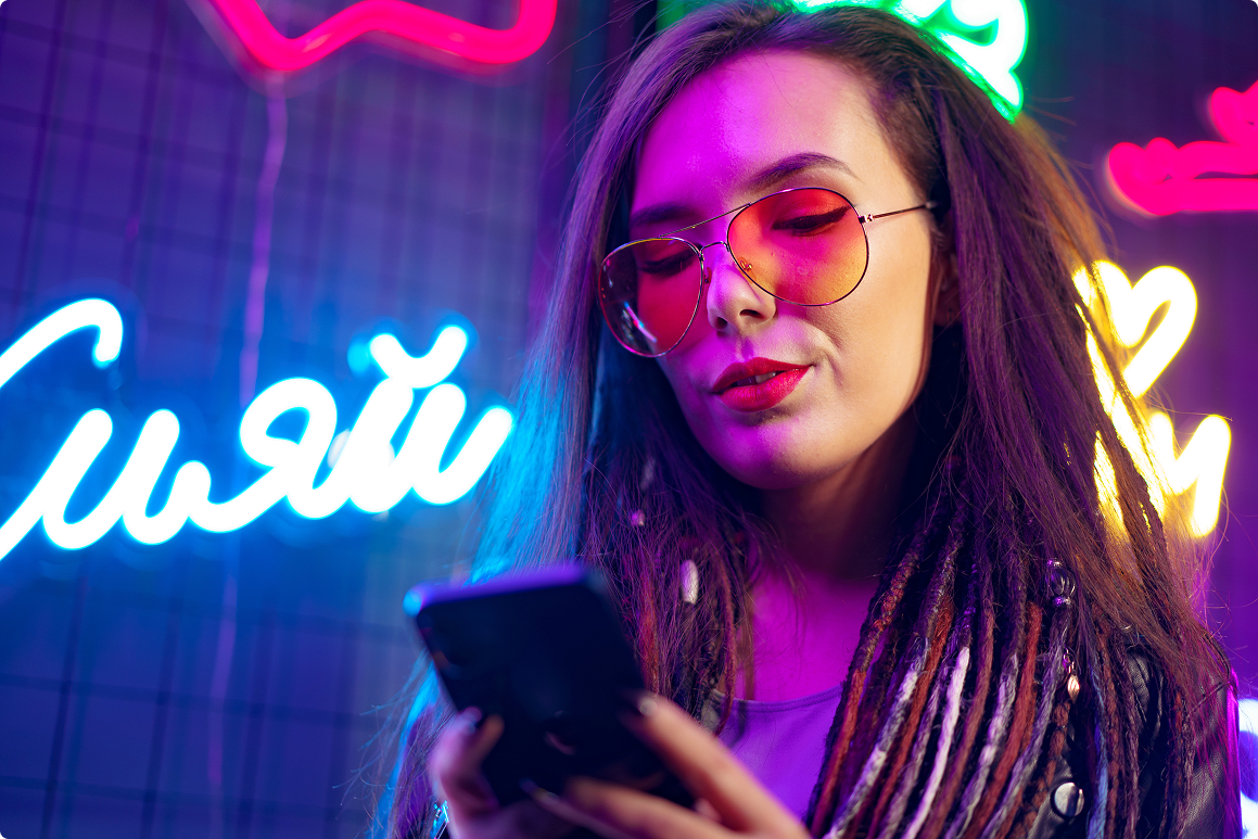 A white lady wearing sunglasses in a club looking at her phone